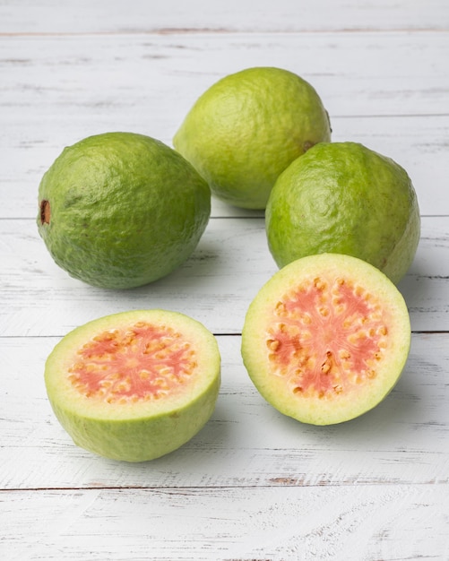 Guayabas rojas y medias frutas sobre mesa de madera.