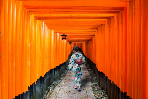 Gueixas entre Tori Gate de madeira vermelha no santuário de Fushimi Inari em Kyoto, Japão.