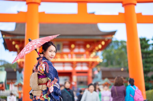 Gueixas vestindo quimono japonês entre o tori gate de madeira vermelha no santuário fushimi inari