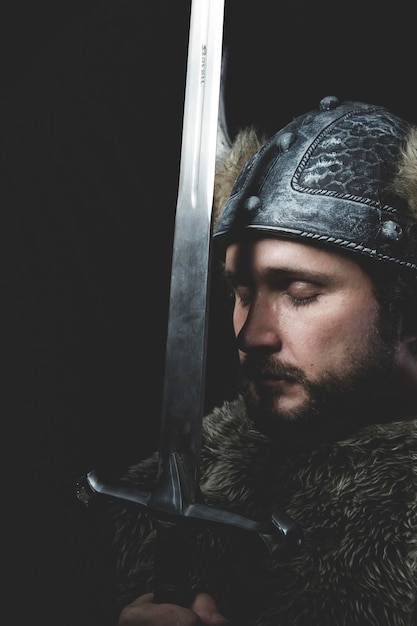 Foto guerra, guerrero vikingo con espada de hierro y casco con cuernos