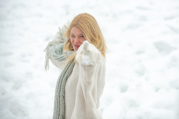 Guerra de nieve. Gente en la nieve. Retrato de una mujer joven en la nieve tratando de calentarse. Alegre