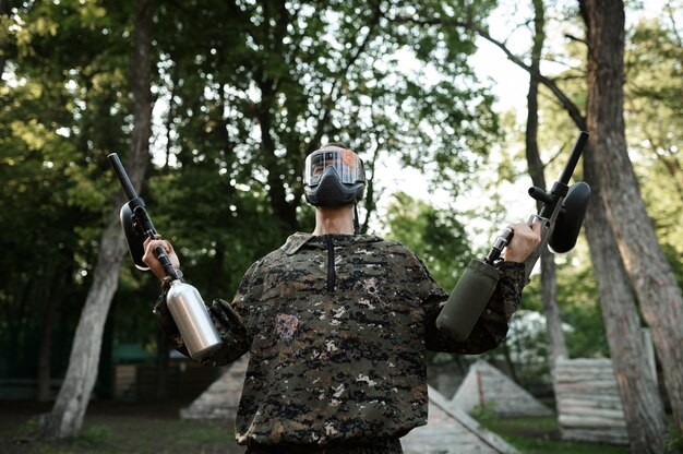 Guerreiro de paintball posa em playground na floresta