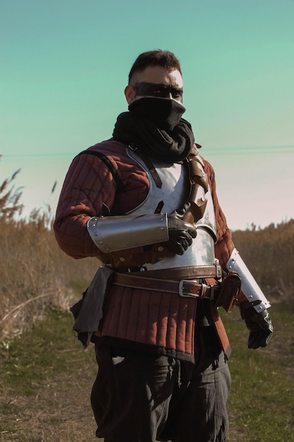 Foto guerrero medieval en el bosque, portando una espada y una antorcha.