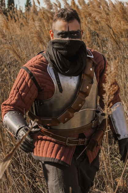 Foto guerrero medieval en el bosque, levando uma espada e uma tocha.