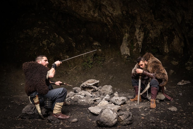 Foto guerreros con armas sentados en una roca en el bosque