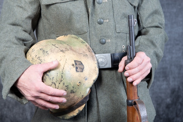 Gürtel und Helm des deutschen Soldaten in Jacke des Zweiten Weltkriegs