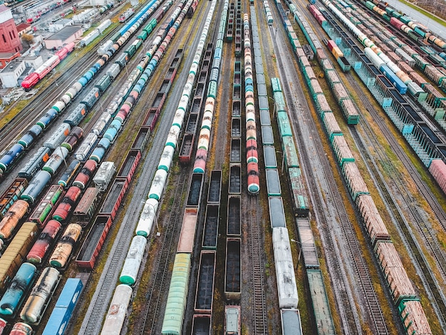 Güterzüge. Vogelperspektive von bunten Güterzügen auf dem Bahnhof. Wagen mit Waren auf der Eisenbahn. Schwerindustrie. Industrielle Begriffsszene mit Zügen. Blick vom fliegenden Drohne.