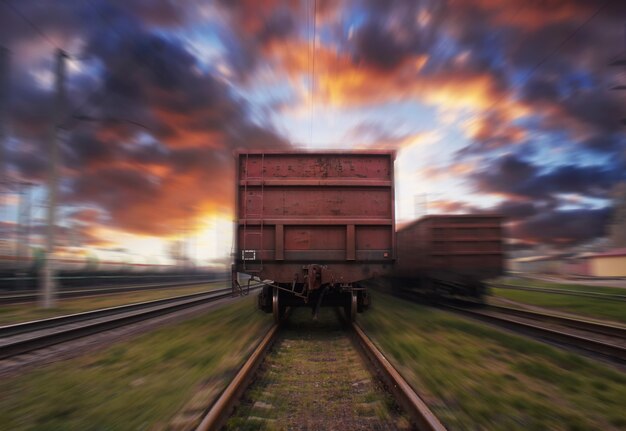 Güterzug in Bewegung mit Unschärfeeffekt gegen den Sonnenuntergangshimmel mit Wolken.