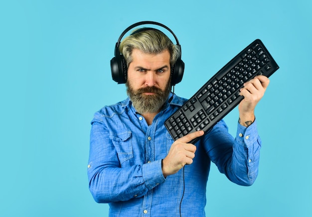 Guia de construção de PC para jogos Configurações gráficas forçadas ao limite Vício em jogos Jogos on-line Lazer moderno Jogar jogos de computador Homem barbudo hipster gamer fones de ouvido e teclado Executar qualquer jogo moderno