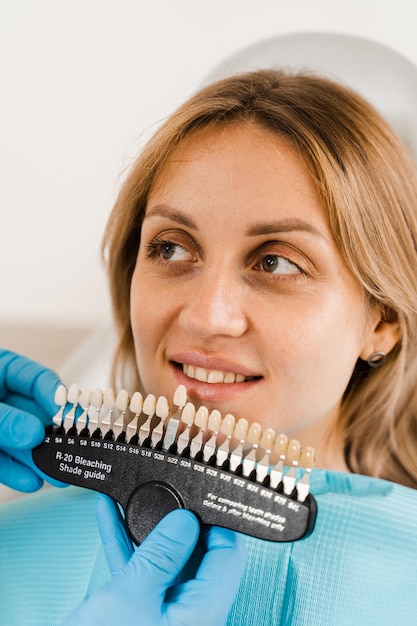 Guía de tonos de color de dientes con paciente mujer Blanqueamiento de dientes Dentista trabajando con muestras de coincidencia de color de dientes en clínica dental Odontología