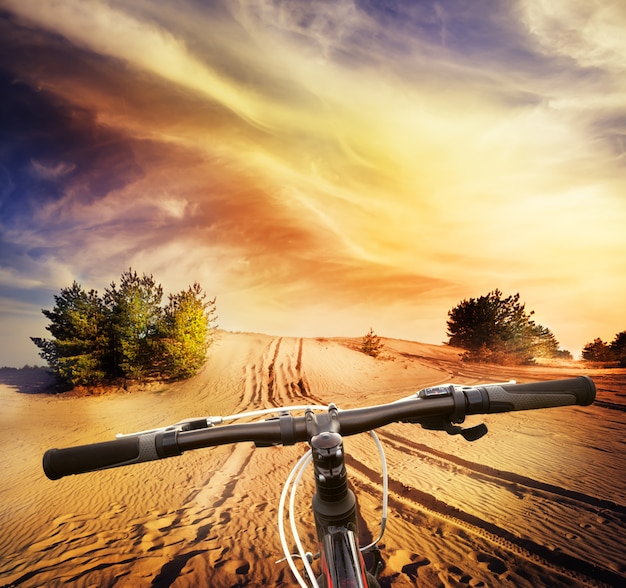 Guiador de bicicleta na areia do deserto