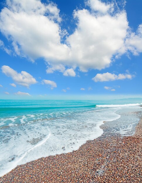 Foto guijarros y olas bajo un cielo nublado en la playa de platamona cerdeña