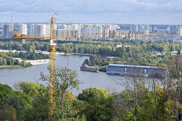 Guindaste de construção no fundo de edifícios residenciais e o Rio Dnieper