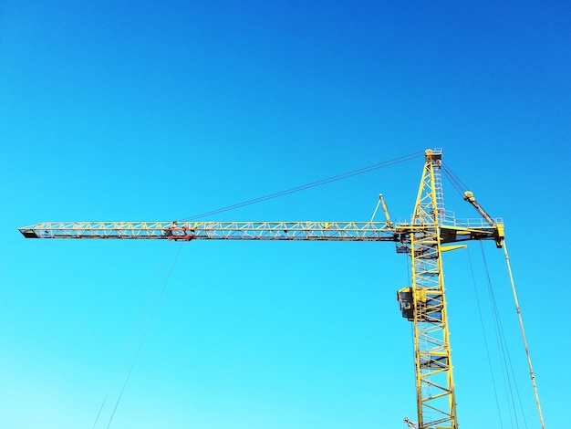 Guindaste de torre amarelo sobre um fundo de céu azul.