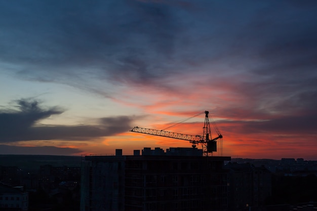 Guindaste de torre e silhueta do canteiro de obras ao nascer do sol