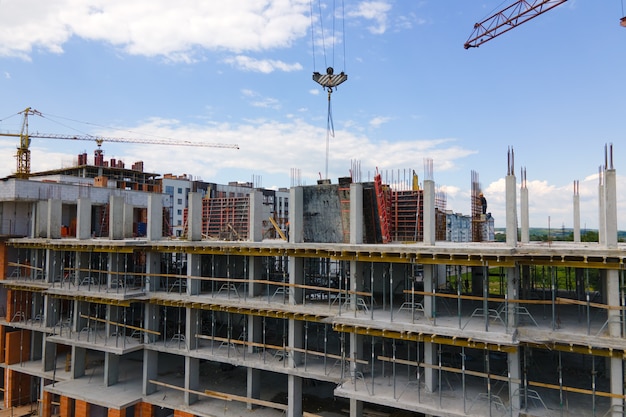 Guindaste de torre em alto edifício residencial de concreto em construção. Conceito de desenvolvimento imobiliário.