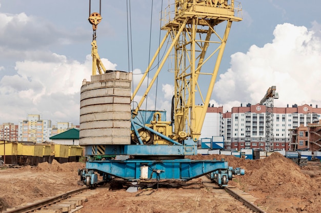 Guindaste de torre em close-up de trilhos no canteiro de obras no contexto do céu nublado. close-up de equipamento de construção pesado para levantamento e movimentação de cargas. guindaste de construção.