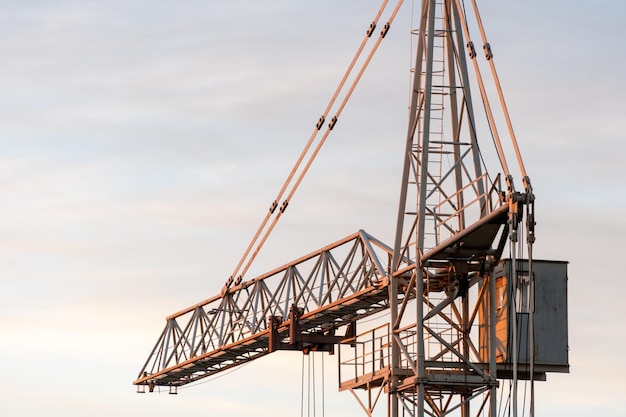 Guindaste de torre no fundo do céu ao pôr do sol O boom de um guindaste de construção fechado