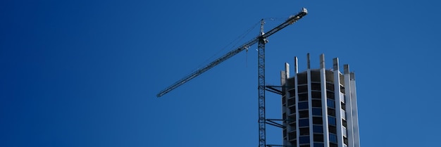 Guindaste e canteiro de obras contra a construção do céu azul do conceito de edifícios altos