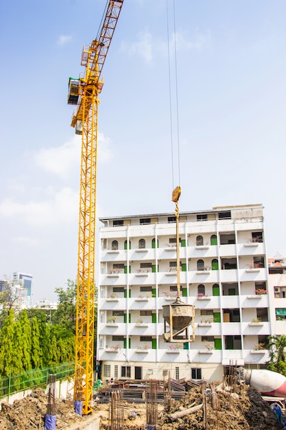 Guindaste é usado na construção de edifícios altos para ferramenta de grande indústria sob o céu azul e nuvens brancas.