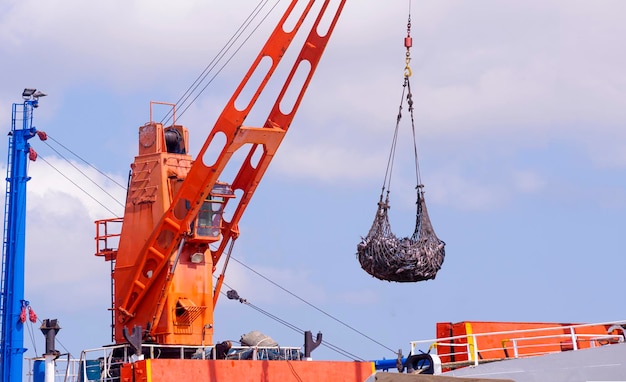 Guindaste em grande barco de pesca está levantando atum para transferir para caminhão refrigerado no porto