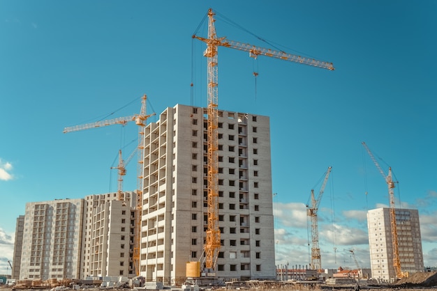 Foto guindastes altos e construção de casas altas