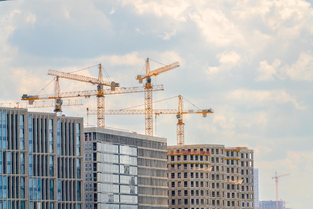 Guindastes de construção perto da fachada de uma casa em construção moderna indústria de construção Venda e aluguel de imóveis