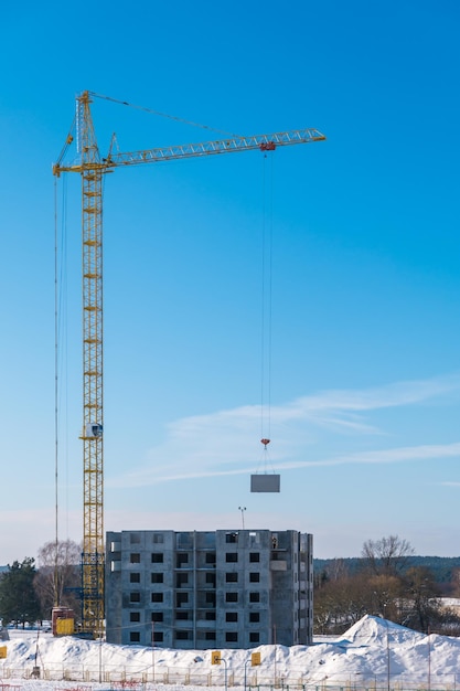 Guindastes de torre e vários andares inacabados perto de edifícios em construção no dia ensolarado de inverno