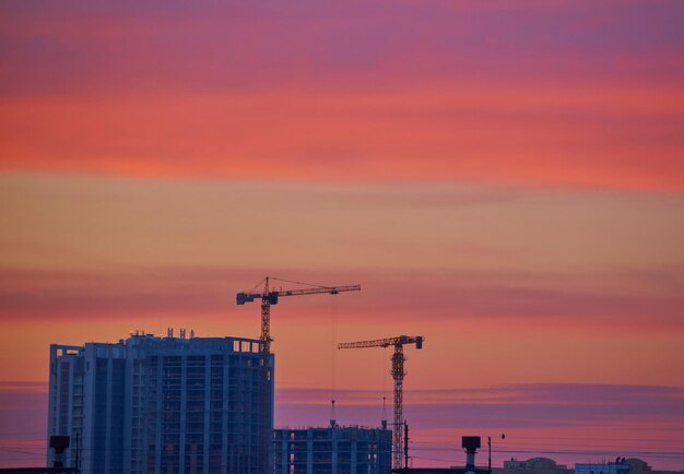 Guindastes em um canteiro de obras ao pôr do sol