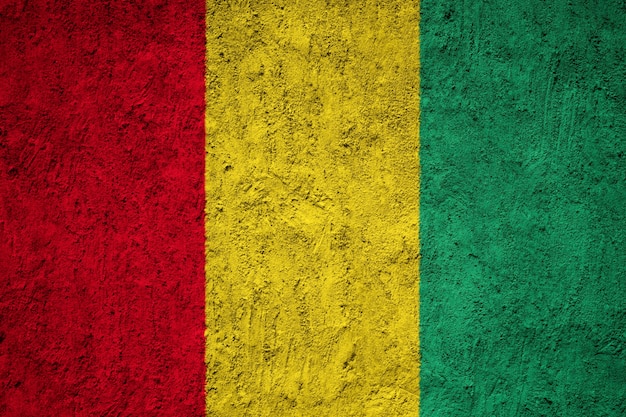 Guinea-Flagge auf Grunge-Wand gemalt