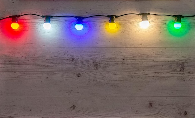 Guirlanda de lâmpadas coloridas no fundo de madeira pálida