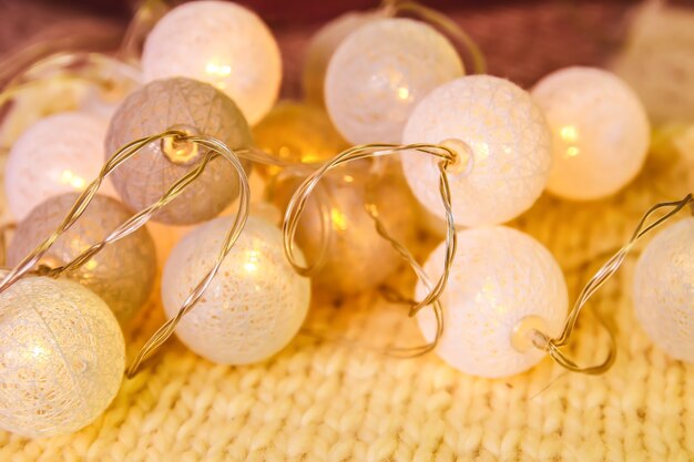 Foto guirlanda de luzes de natal com lanternas redondas em fundo de tecido de malha.