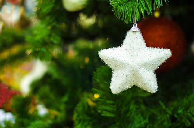 Guirlanda de Natal, bolas, luzes, brinquedos, figura decorativa branca estrela de prata na árvore de Natal. decoração de casa no ano novo.