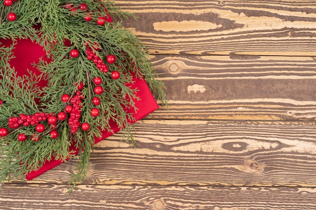 Guirlanda de Natal com bagas vermelhas de inverno em uma mesa de madeira, úteis como pano de fundo de Natal