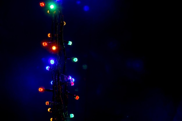 Foto guirlanda de natal e ano novo com luzes multicoloridas brilhantes no espaço de cópia de fundo isolado preto