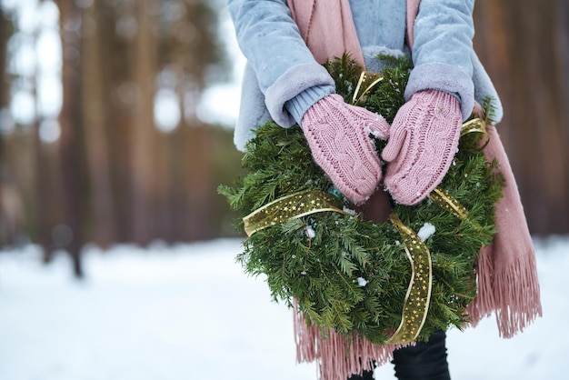 Guirlanda de Natal em mãos de mulher bonita na floresta de neve. feriados sazonais, adornando. Natal.