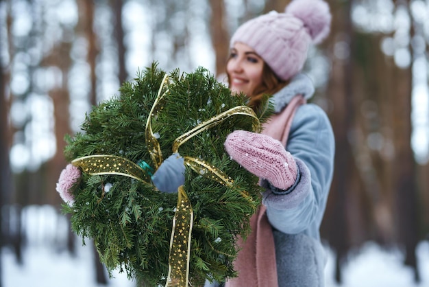 Guirlanda de Natal em mãos de mulher bonita na floresta de neve. feriados sazonais, adornando. Natal