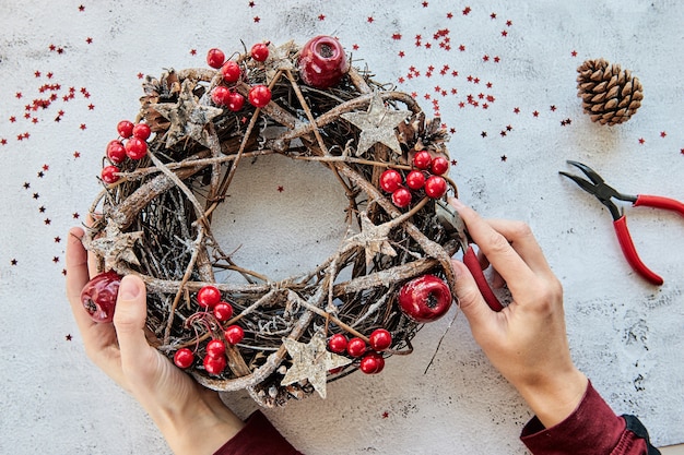 Guirlanda de natal feita de ramos decorados com estrelas douradas de madeira e bolhas vermelhas de frutas vermelhas.