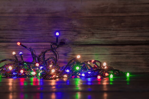 Guirlanda elétrica com lâmpadas multicoloridas em superfície de madeira