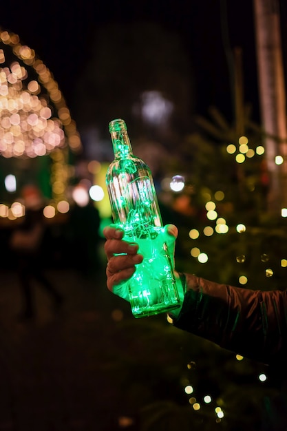 Guirlanda verde na garrafa no fundo da cidade à noite festiva