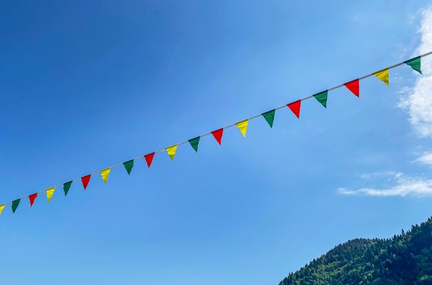 Foto guirlandas multicoloridas ou bandeiras voam no vento em um dia ensolarado de verão com um céu azul com nuvens