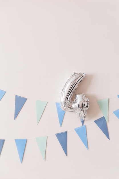 Guirnalda de banderas de papel azul en la pared blanca con globo plateado número cuatro