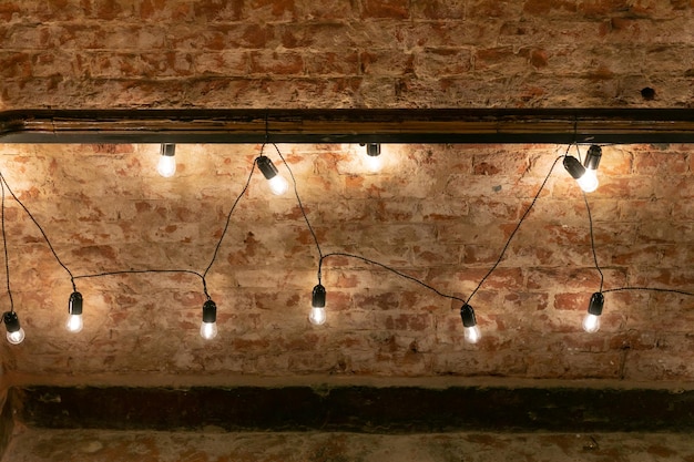 Foto una guirnalda de bombillas cálidas decoración festiva de un evento en el loft con fondo de pared de ladrillo