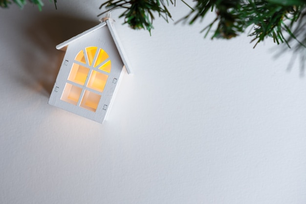 Guirnalda de casa de madera brillante en un árbol de Navidad sobre un fondo blanco.