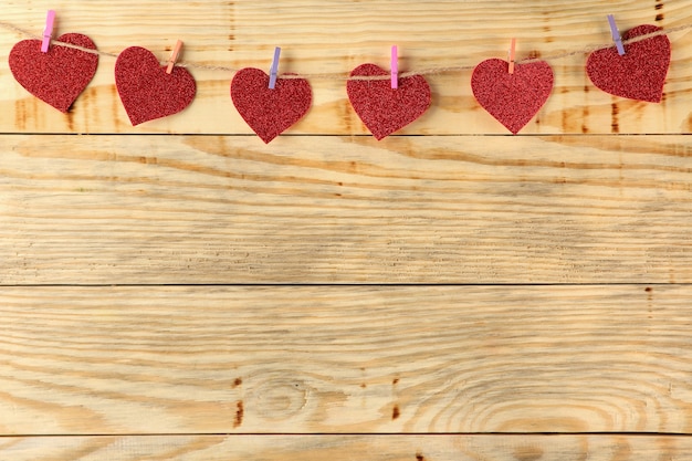 Una guirnalda de corazones en pinzas para la ropa sobre un fondo de madera natural Día de San Valentín.