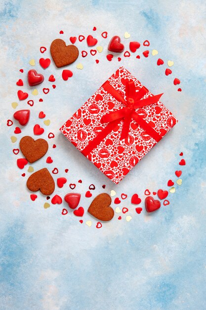 Guirnalda de dulces, galletas y figuras de corazón con caja de regalo sobre fondo azul.