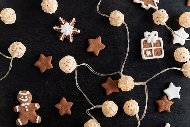 Guirnalda y galletas de Navidad glaseado de azúcar glas sobre fondo negro.