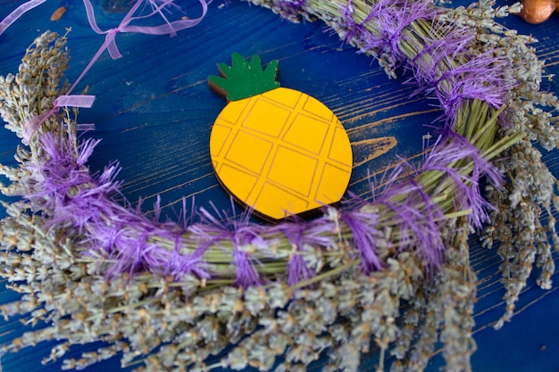 Guirnalda de lavanda y piña amarilla sobre una tabla de madera azul