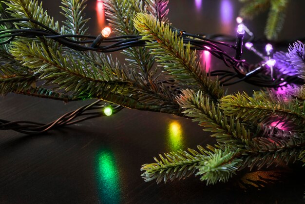 Guirnalda de luces led de colores en primer plano de rama de árbol de navidad artificial