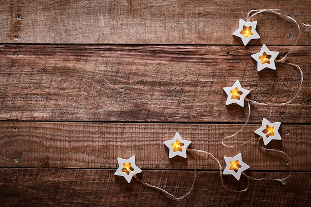 Guirnalda de Navidad con estrellas de luz de madera sobre fondo antiguo de madera oscura. Vista superior con espacio de copia. Tarjeta de felicitación de Navidad.